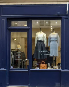 Vitrine de la boutique Fabrique by Ambali à Paris, présentant des mannequins habillés et un sac en cuir dans un décor élégant.