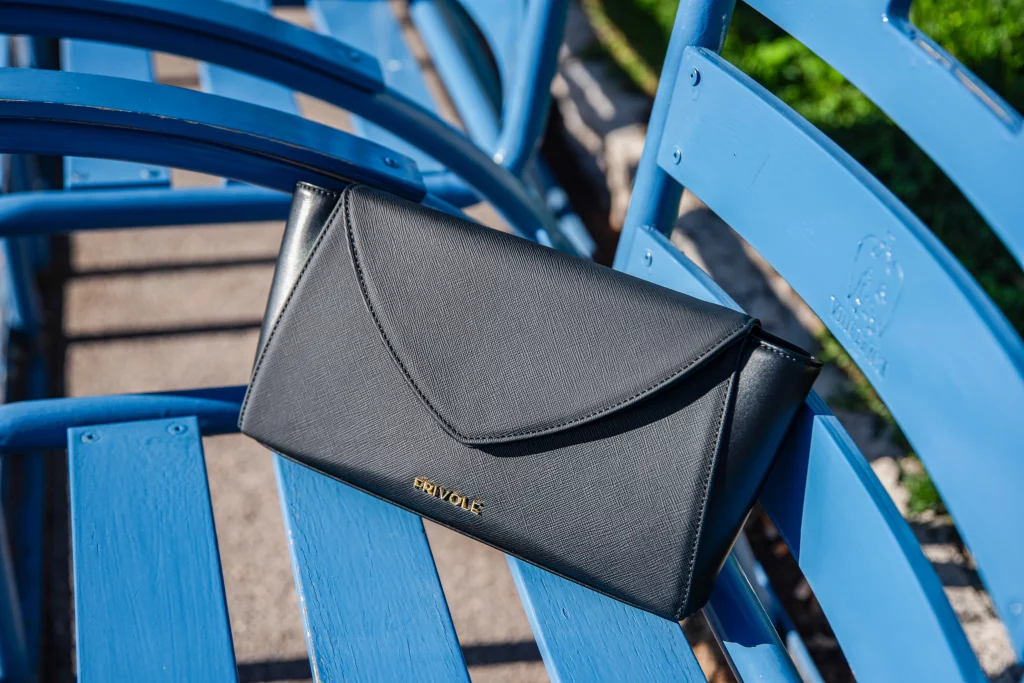 Sac Frivole noir posé sur une chaise bleue sur la Promenade des Anglais à Nice